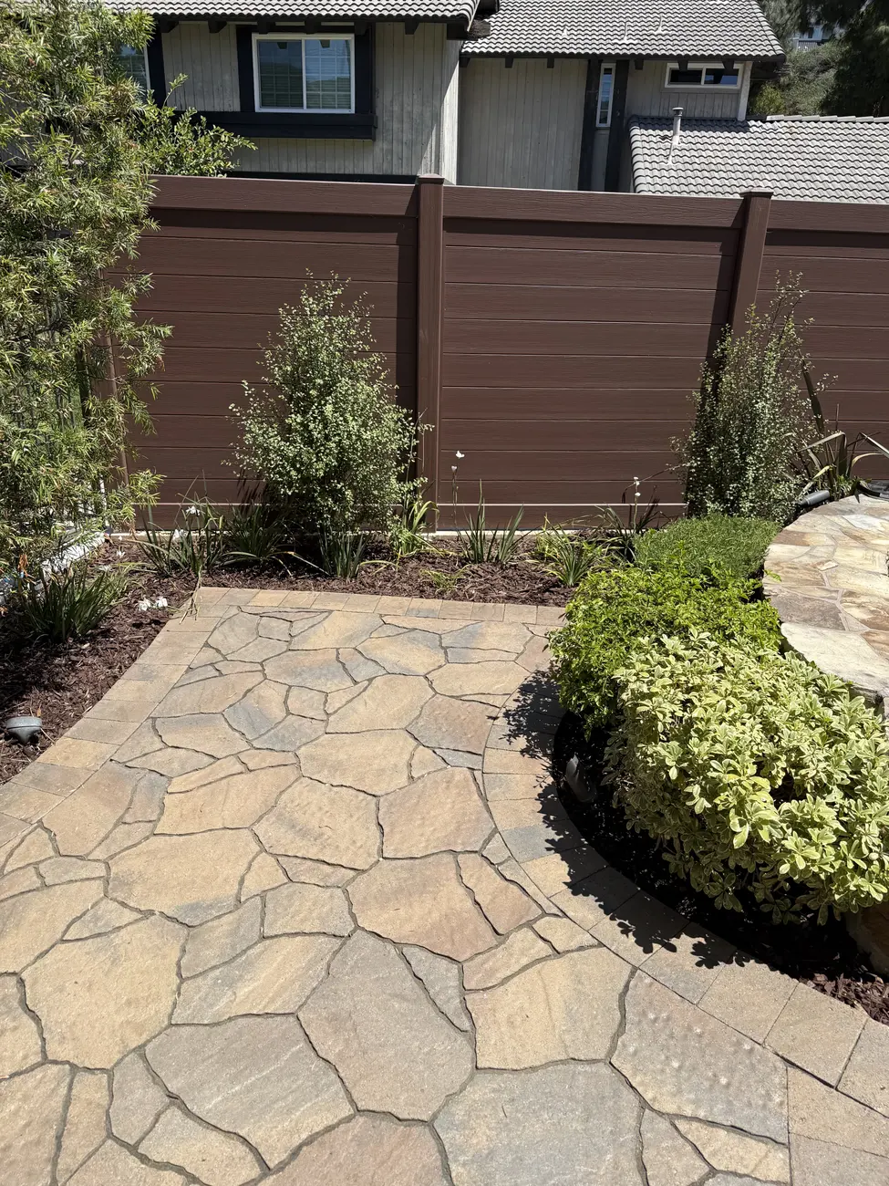 Flagstone patio with planting beds and privacy fence