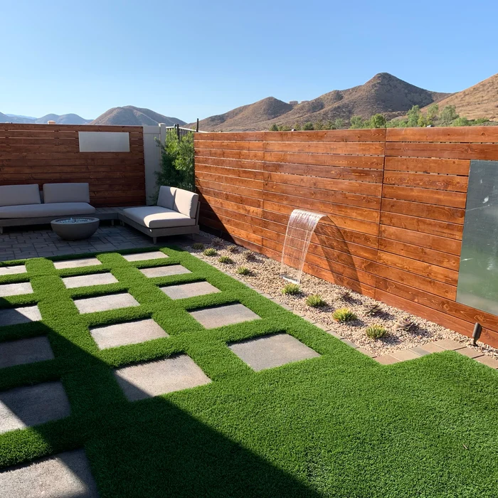 Modern backyard with wood privacy wall water feature, paver and turf grid