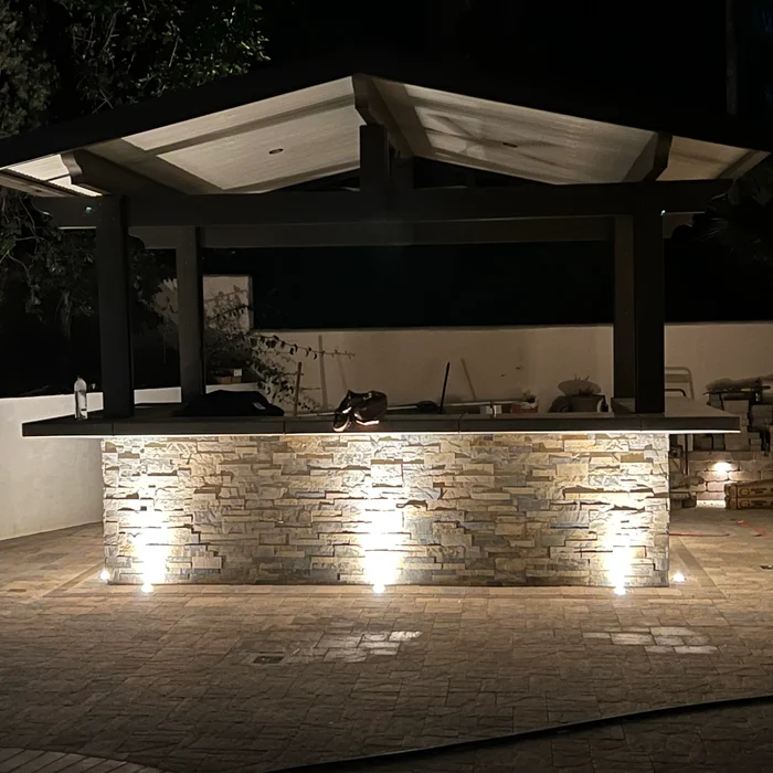 Outdoor kitchen and BBQ island with landscape lighting at night