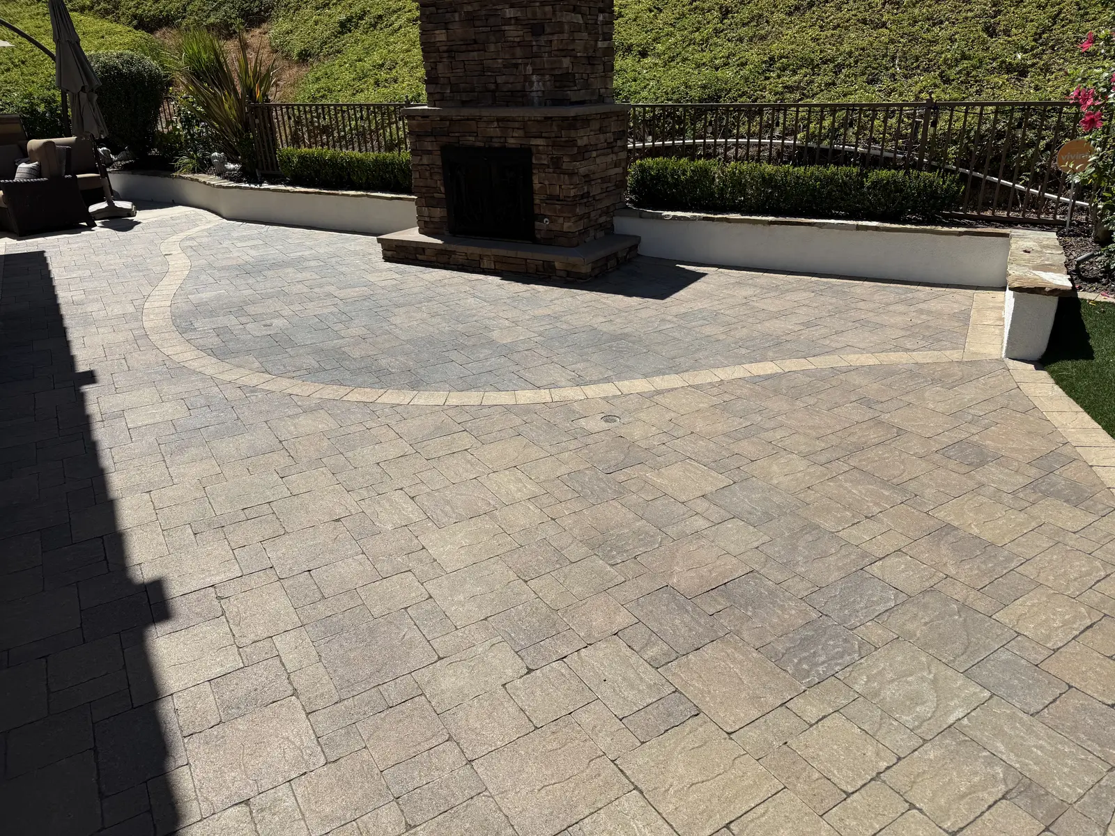 Paver patio with built-in outdoor fireplace and seating area by Valley Pacific Landscape